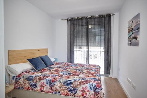 拉斯加莱塔斯Apartamento Sol y Mar的一间卧室配有一张带五颜六色的被子的床和窗户