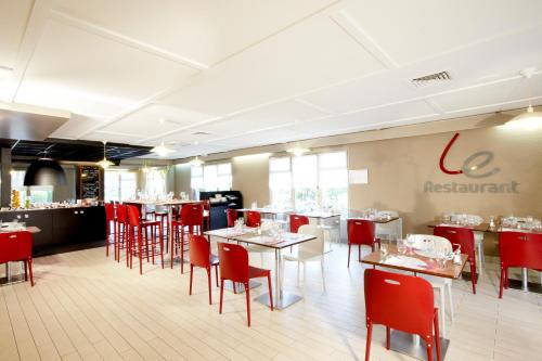 比亚里茨钟楼比亚丽兹酒店的一间设有红色桌椅的用餐室和一间餐厅