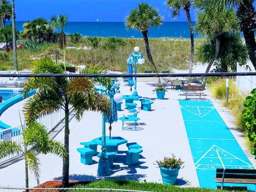 圣徒皮特海滩约翰斯通海滩汽车旅馆 的一个带蓝色桌椅的游泳池以及大海