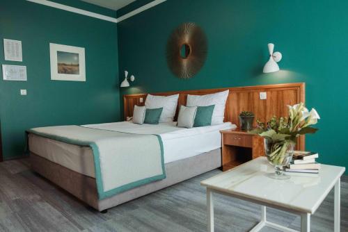 贾科沃达科沃酒店的一间卧室配有一张带绿色墙壁的床和一张桌子