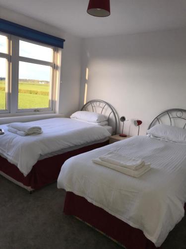 基尔马诺克Ayrshire cottage的带窗户的客房内的两张床