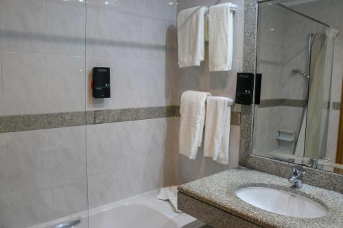 奥尔塔奥尔塔酒店的一间带水槽、浴缸和镜子的浴室