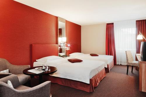 埃格尔金根埃格尔金根瑞享酒店的酒店客房带两张床和一张桌子以及椅子。