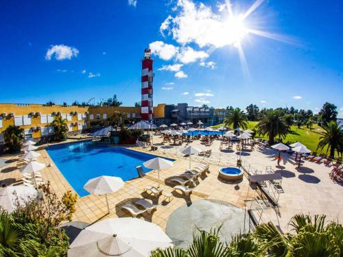 特尔马斯德里奥翁多玛丽娜德尔法鲁度假酒店的一个带椅子和遮阳伞的游泳池和一个灯塔