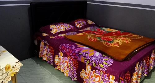 布罗莫Holiday Home Anggun Bromo的一张带紫色棉被和鲜花的床