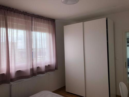 萨格勒布Apartman STAR的卧室配有白色橱柜和窗户。