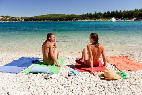 弗尔萨尔Koversada Villas Naturist Park的两个人坐在海滩上