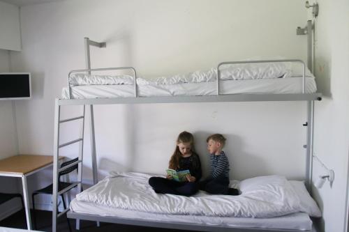 尼克宾法尔斯特Nykøbing Falster Vandrehjem的两个孩子坐在双层床上读书