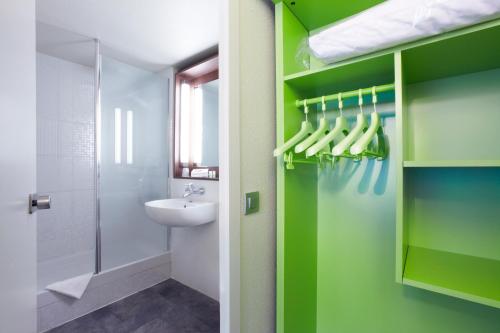 布雷斯特布雷斯特钟楼酒店 - 古埃斯努机场酒店的浴室设有绿色的墙壁、水槽和淋浴。