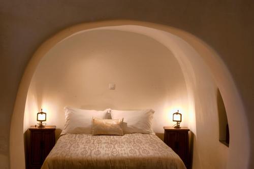 伊亚Heliophos Boutique Caves的卧室配有一张床,两边都配有两盏灯