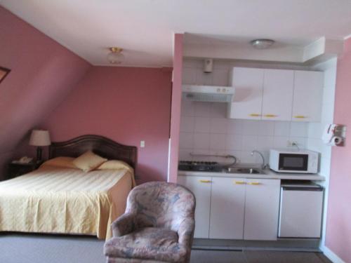 蒙特港科隆公寓式酒店的一间卧室配有一张床、一把椅子和一台微波炉