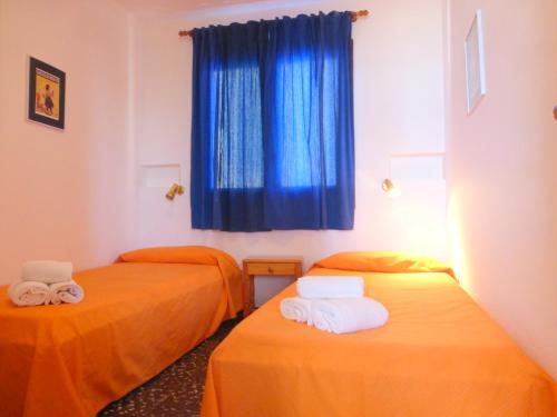 霍斯皮塔勒·德尔英福Rentalmar El Capitan的蓝色窗户的客房内配有两张橙色床