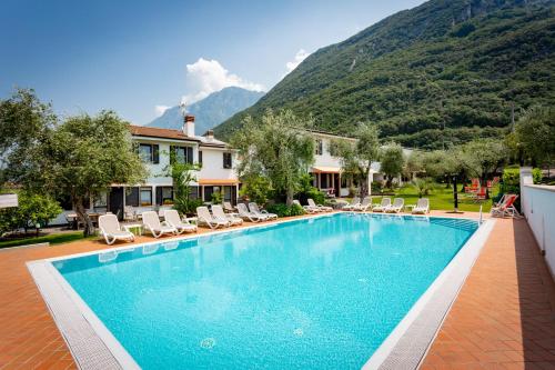 马尔切西内Residence Alesi的一个带椅子的游泳池、一座房子和一座山脉