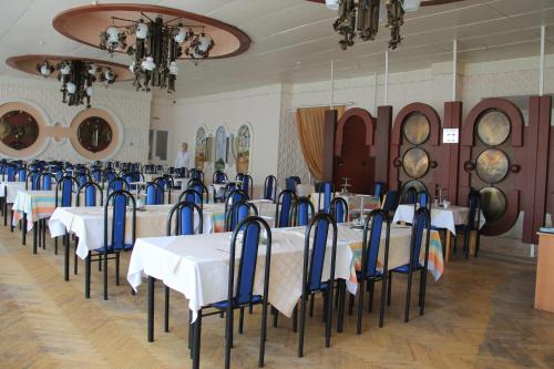 热列兹诺沃德斯克Zheleznovodskaya Klinika Sanatorium的用餐室配有白色的桌子和蓝色的椅子
