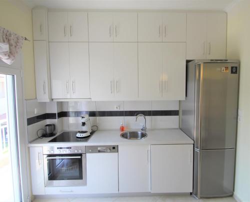 艾斯普罗瓦塔Emotion Apartments的厨房配有白色橱柜和不锈钢冰箱