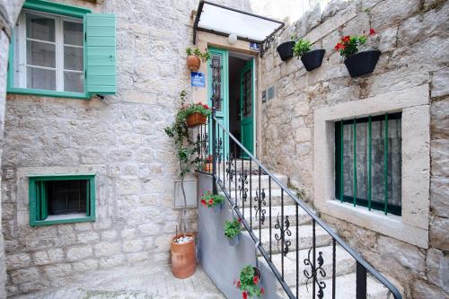 科米扎库尔基斯住宿加早餐旅馆的一座石头房子,设有绿色的窗户和楼梯