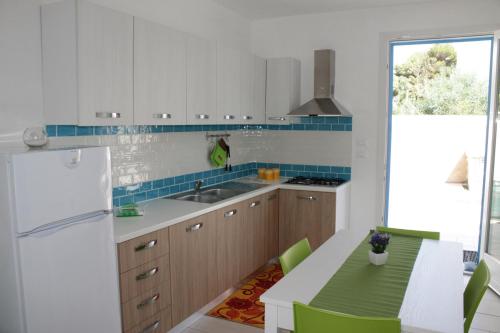 玛丽娜迪曼卡维萨Londazzurra的厨房配有白色冰箱和带绿色椅子的桌子