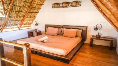 波波约Vibra Guesthouse Popoyo的一间卧室配有带橙色床单和两张桌子的床