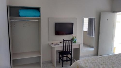 圣代佩德罗Hotel Picadão的一间卧室配有一张桌子、一台电视和一把椅子
