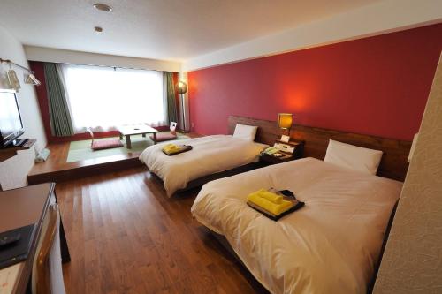 屋久岛屋久岛绿色酒店的酒店客房设有两张床和红色的墙壁。