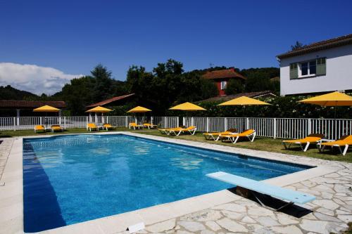 佩戈马布斯克酒店的房屋旁的游泳池配有椅子和遮阳伞