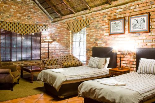 波切夫斯特鲁姆Elgro River Lodge的一间卧室设有两张床和砖墙