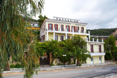 艾迪普索斯Ξενοδοχείο 'ΠΑΛΛΑΔΙΟΝ' Hotel 'PALLADION'的白色的建筑,在街上有红色的窗户