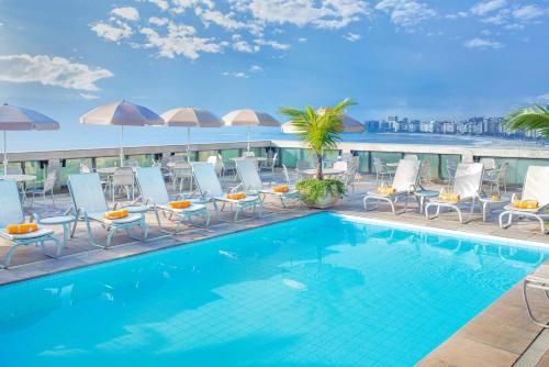 里约热内卢科帕卡巴纳温莎怡东酒店的一座带椅子和遮阳伞的大楼的顶部游泳池