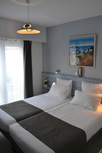 圣皮耶尔基贝龙Hotel De Bretagne的卧室配有一张大白色床和窗户