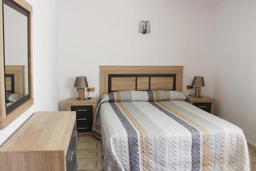 布拉内斯Apartamentos Las Americas - Blanes Beach的一间卧室配有一张床和两张带台灯的桌子。