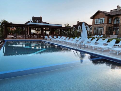 VishenkiWISH Aqua&SPA Resort的一座带白色椅子的游泳池和一座建筑