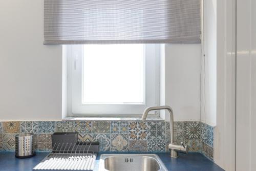 瓦里Syros village suites的带水槽的厨房和带百叶窗的窗户
