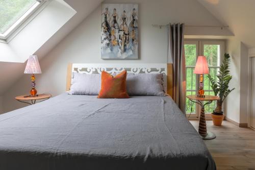 ContinvoirCountry House - La Charbonnière的一间卧室配有一张带橙色枕头的床和两盏灯。
