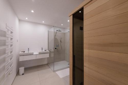 蒂豪尼OliverLux Aparthotel的带淋浴和两个水槽的浴室以及玻璃门。