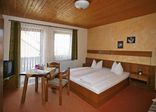 FalkensteinMarias Pension的一间卧室配有一张床、一张桌子和一台电视