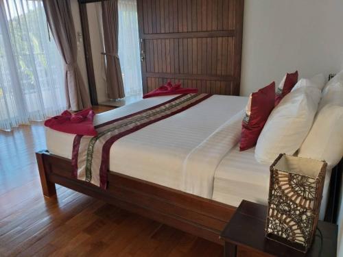 小通奈潘Koh Phangan Pavilions Serviced Apartments的一间卧室配有一张带红色枕头的大床