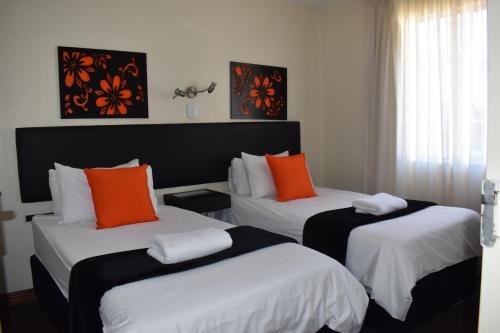 约翰内斯堡Premiere Classe Apartment Hotel的酒店客房 - 带两张带橙色枕头的床