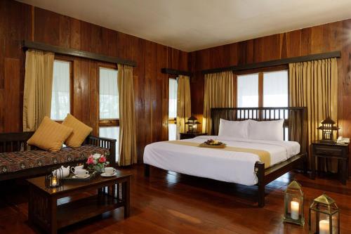清莱帕瓦多尔度假酒店及Spa的卧室配有一张白色的大床和一张沙发。