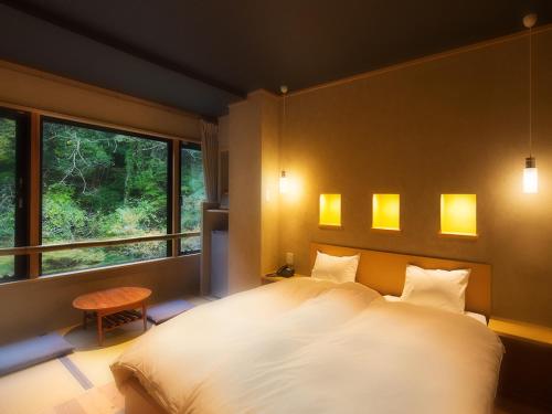 会津若松庄助の宿瀧の湯日式旅馆的卧室设有一张白色大床和一扇窗户。