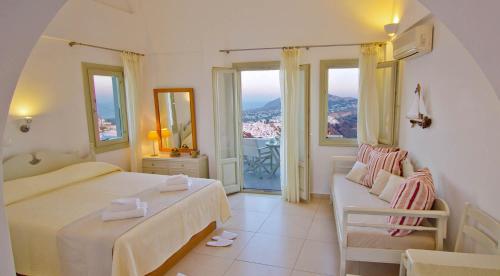 易莫洛林Irida - Santorini的一间卧室设有两张床、一张沙发和窗户。