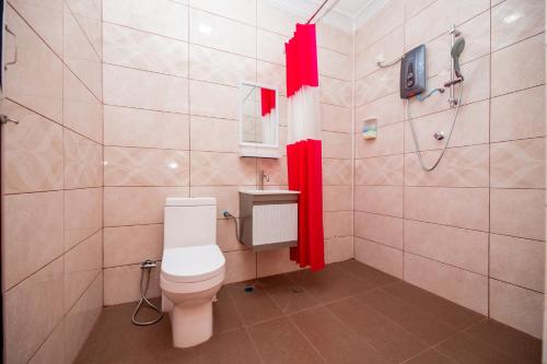 珍南海滩D’ Village Cottage的浴室设有卫生间和带红色窗帘的淋浴。