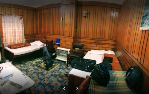 奎达Lourdes Hotel的客房设有三张床、一张书桌和一台电视。