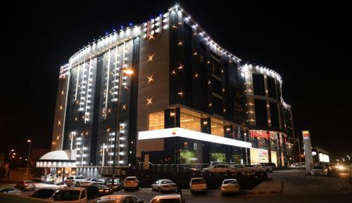 塔伊夫Borj Al Thahabiah ApartHotel的停车场内停放汽车的大型建筑