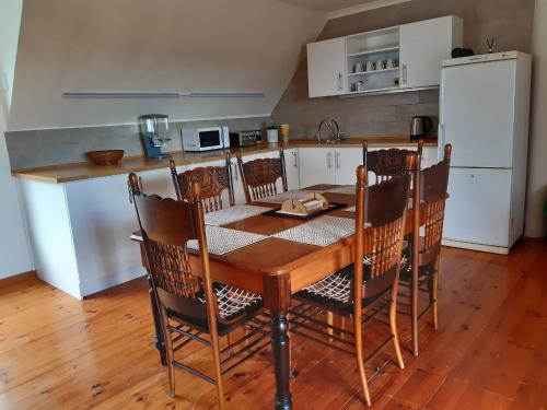 开普敦Vlei Lofts的厨房配有带椅子的木桌和白色冰箱。