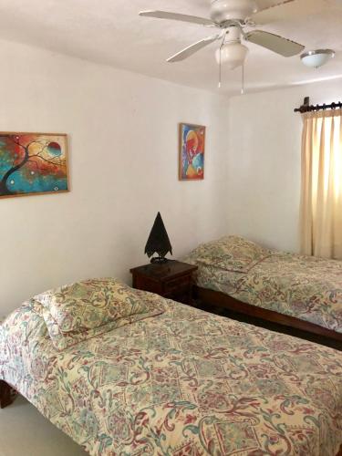 坎昆Ch'ejum bungalow的一间卧室配有两张床和吊扇