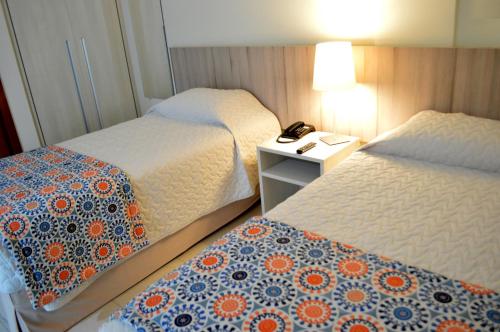 萨尔瓦多卡图萨巴套房度假酒店的酒店客房设有两张床和一张桌子及电话