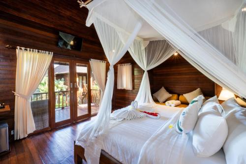蓝梦岛Royal Cottage Nusa Lembongan的卧室配有带白色枕头的天蓬床