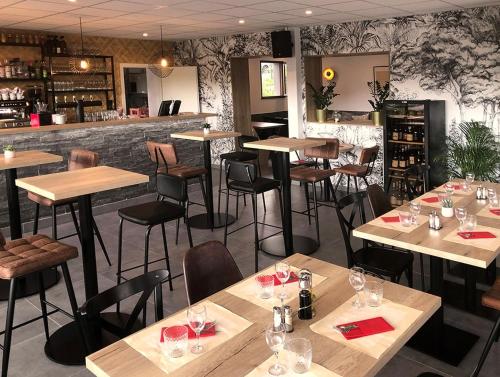 维伊勒佩beaujour & bonsoir Brasserie-Hotel的一间带木桌椅的餐厅和一间酒吧