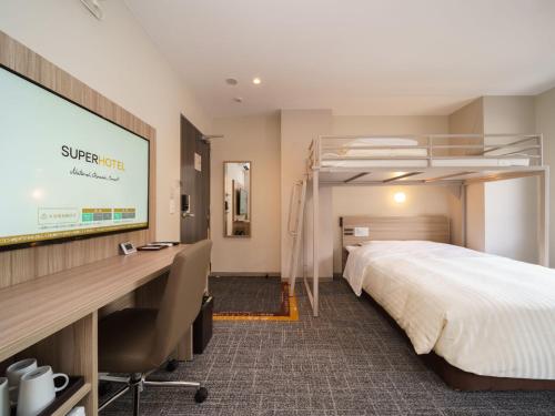 阿南Super Hotel Anan Tomioka的酒店客房,配有床和投影屏幕