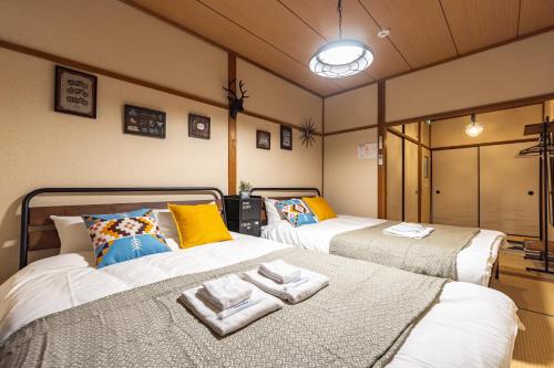 大阪Chachamaru Osaka Castle Park的一间设有两张床铺和毛巾的房间